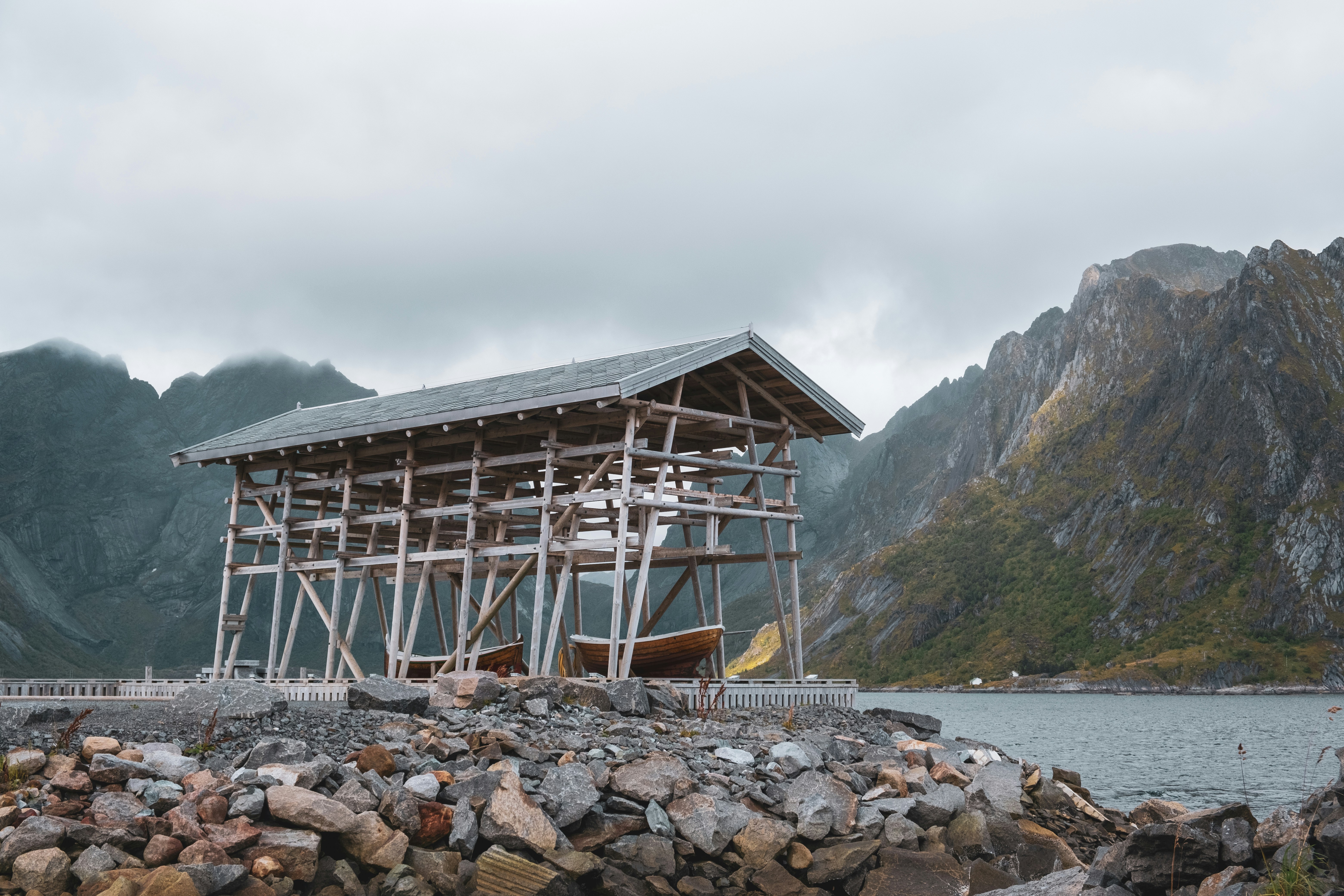 A timber boathouse beneath steep mountains beside a Norwegian fjord
